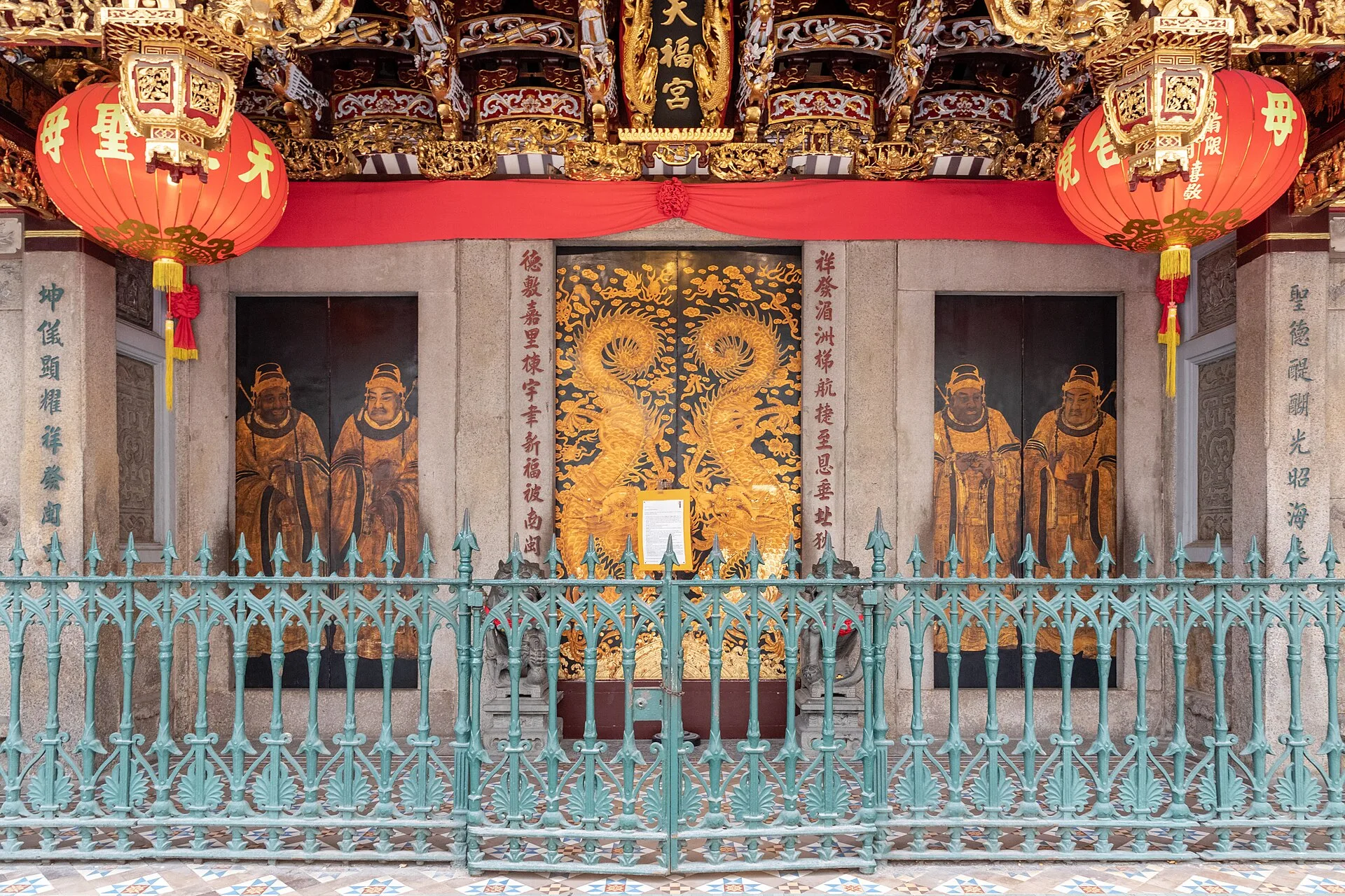 Temple entrance with carved gilded doors, red lanterns and railings