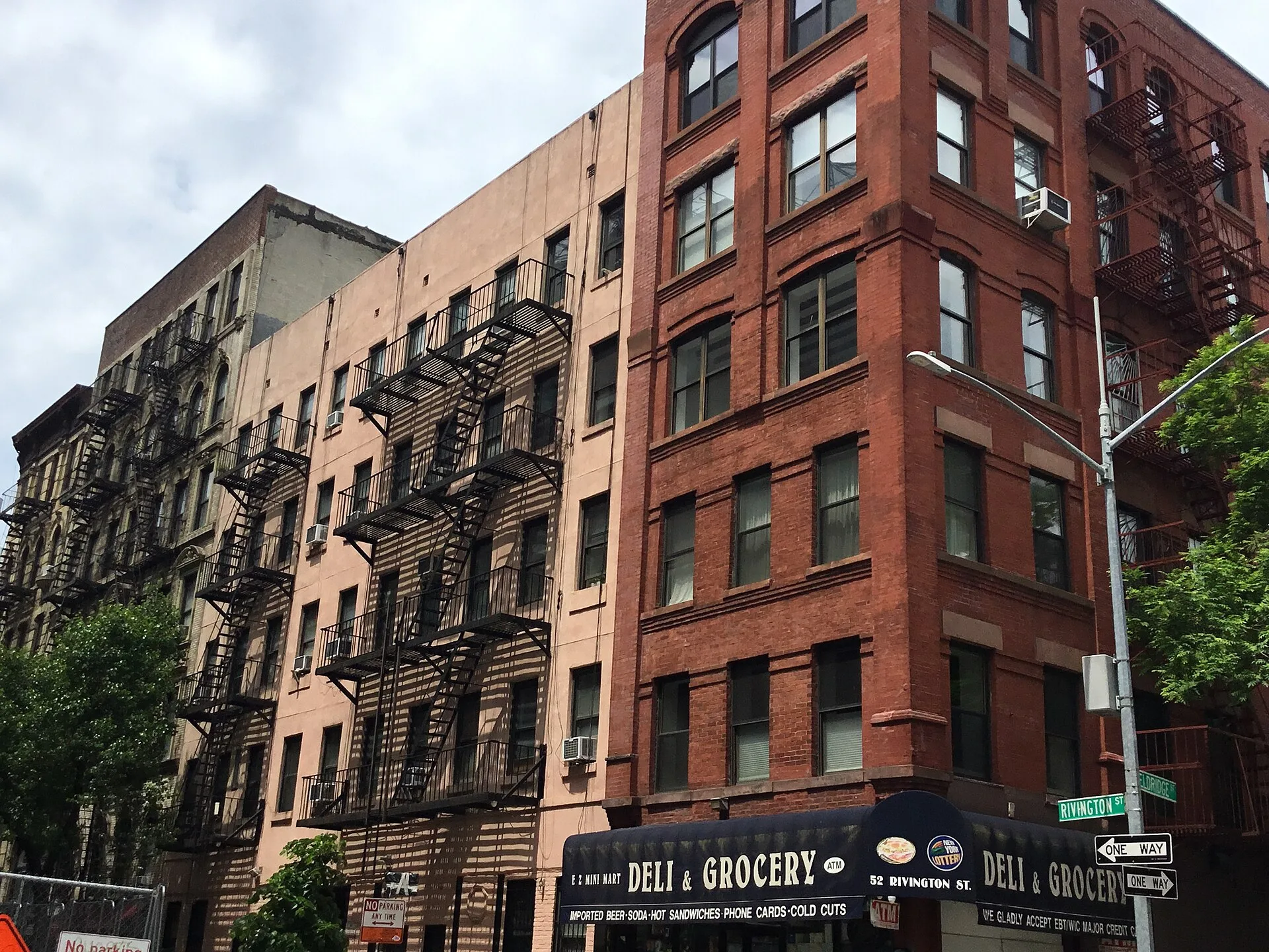 Brick tenement buildings with fire escapes along a Manhattan street