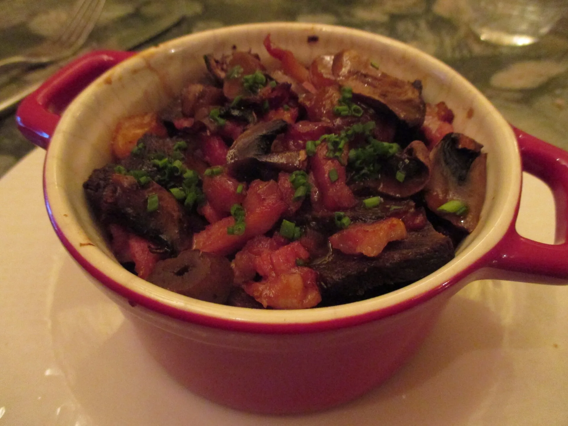 Beef stew with carrots and herbs served in a small red casserole dish