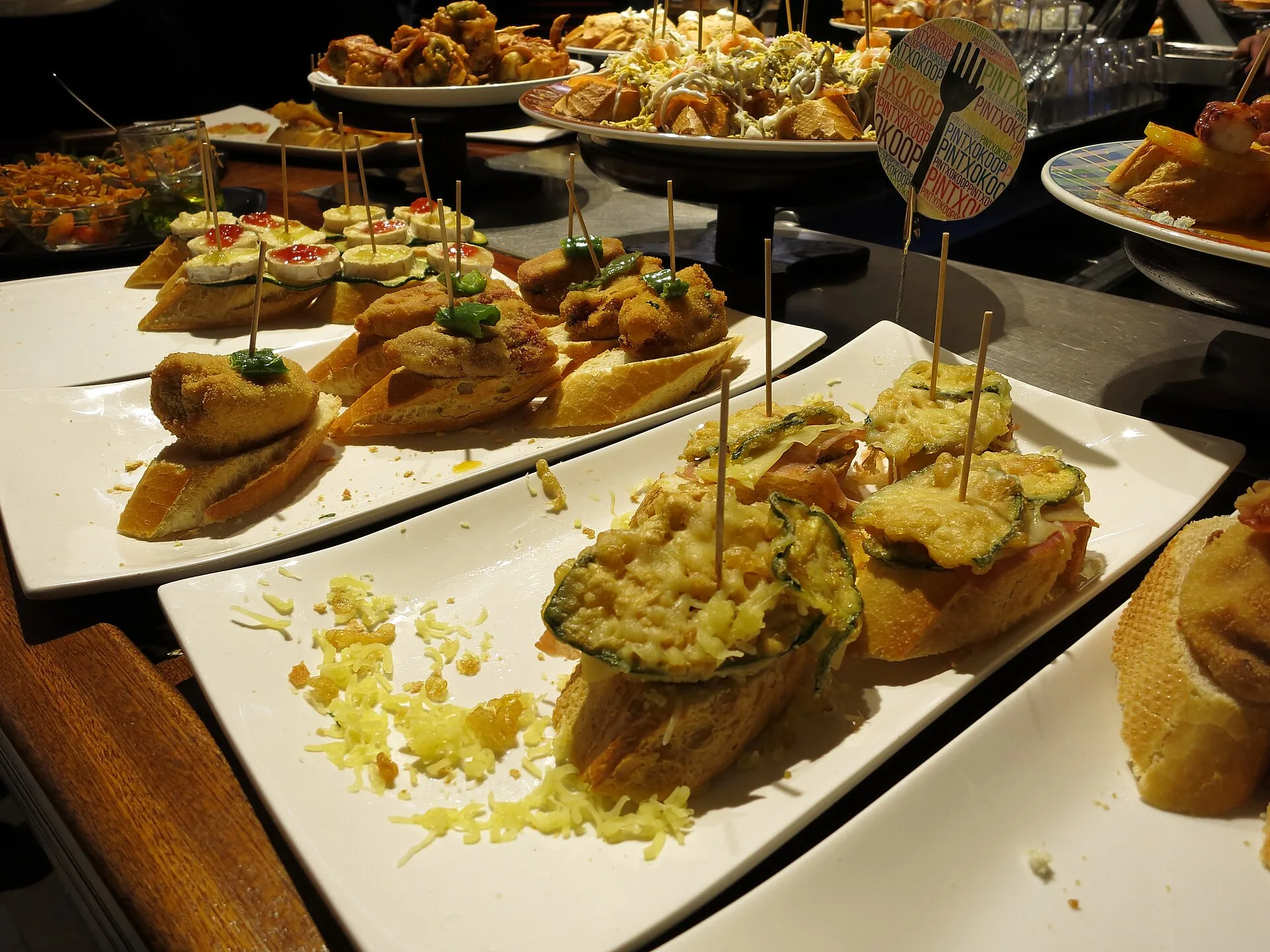 Pintxos on slices of bread held with cocktail sticks on white plates