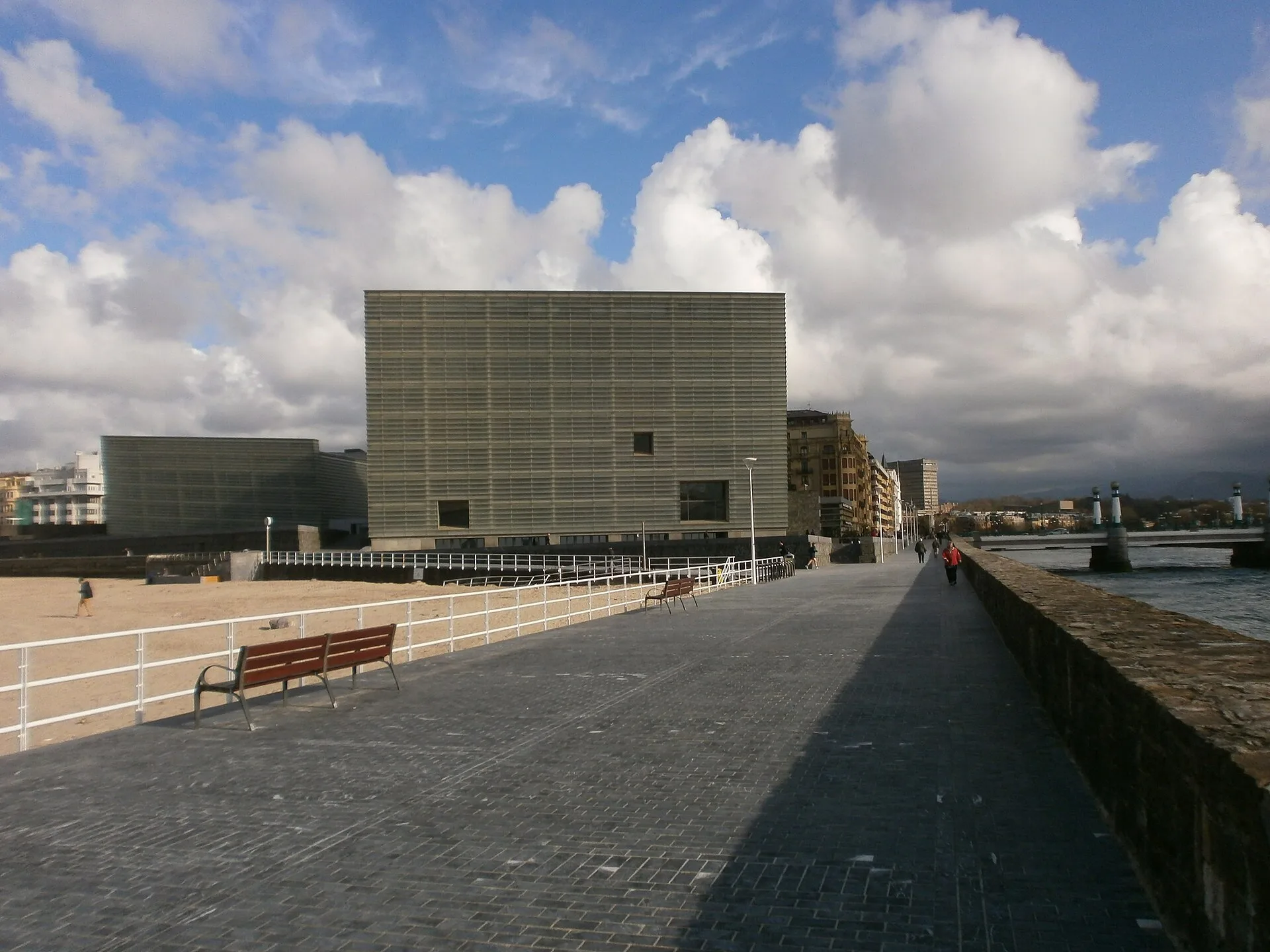 Translucent glass cube building at the end of a seafront promenade
