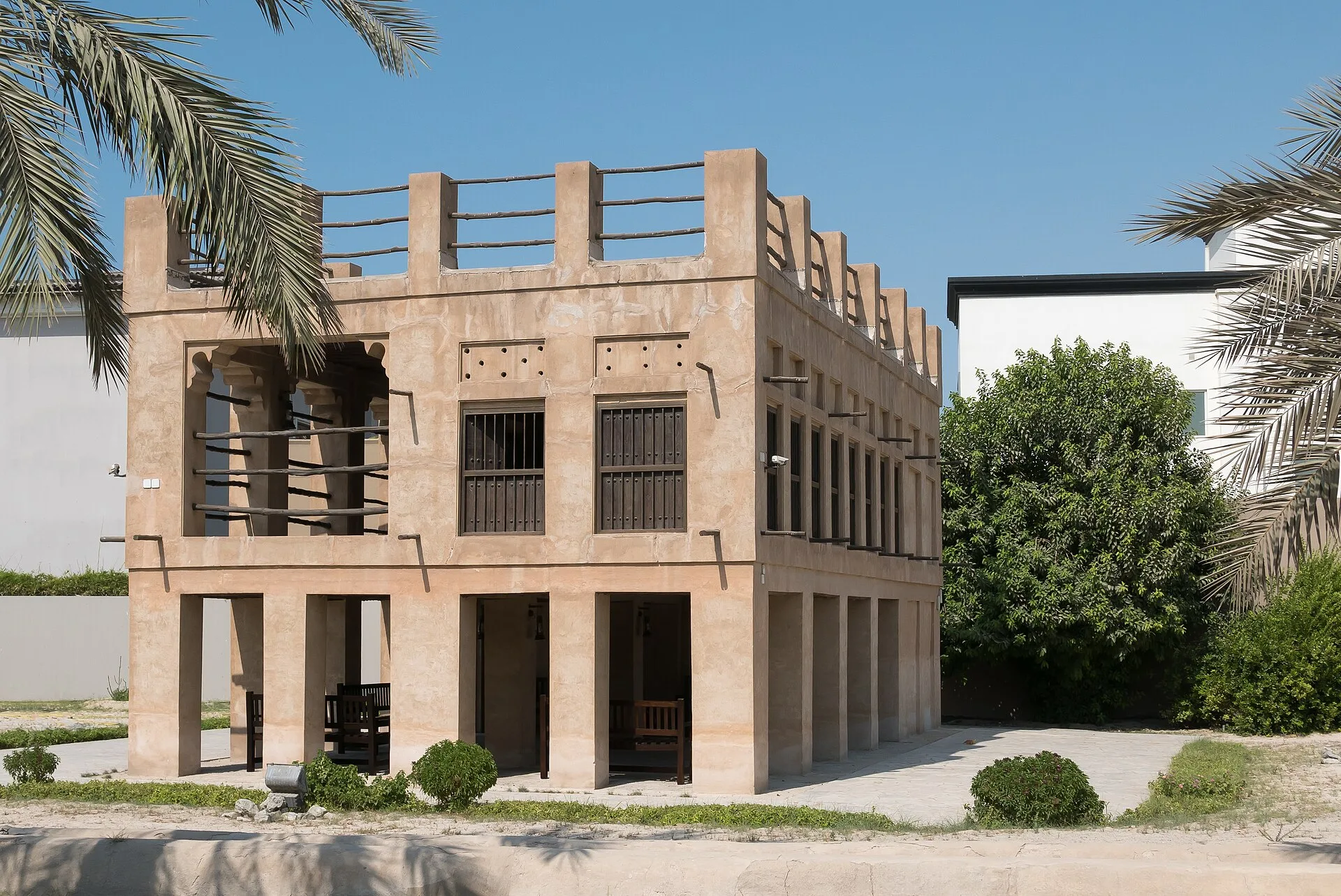 Two-storey coral stone building with open upper verandah and palm trees