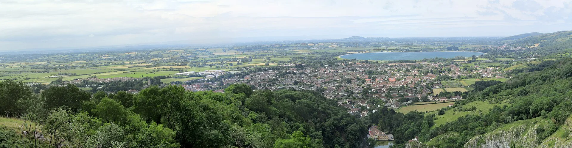 Panoramic view over a village, fields and a reservoir from a hilltop