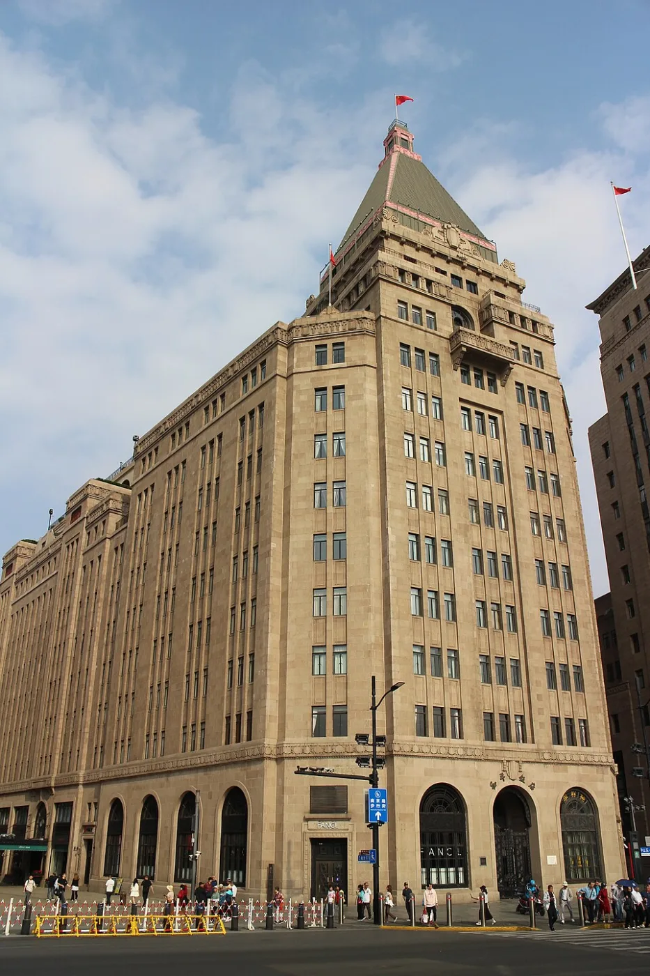 Stone Art Deco tower with a steep pyramid roof on a street corner