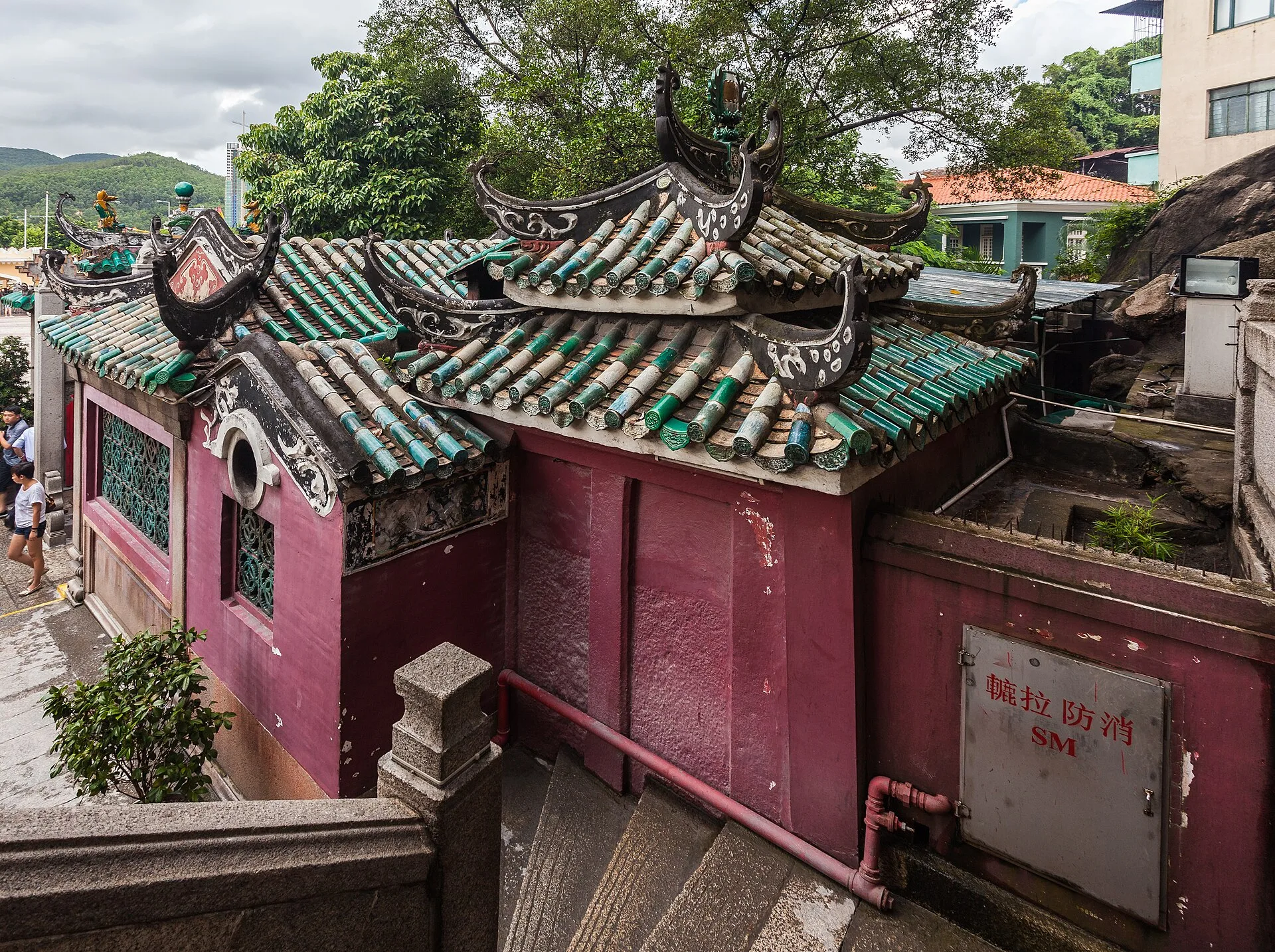 Red-walled temple pavilions with green tiled roofs and carved ridge ornaments