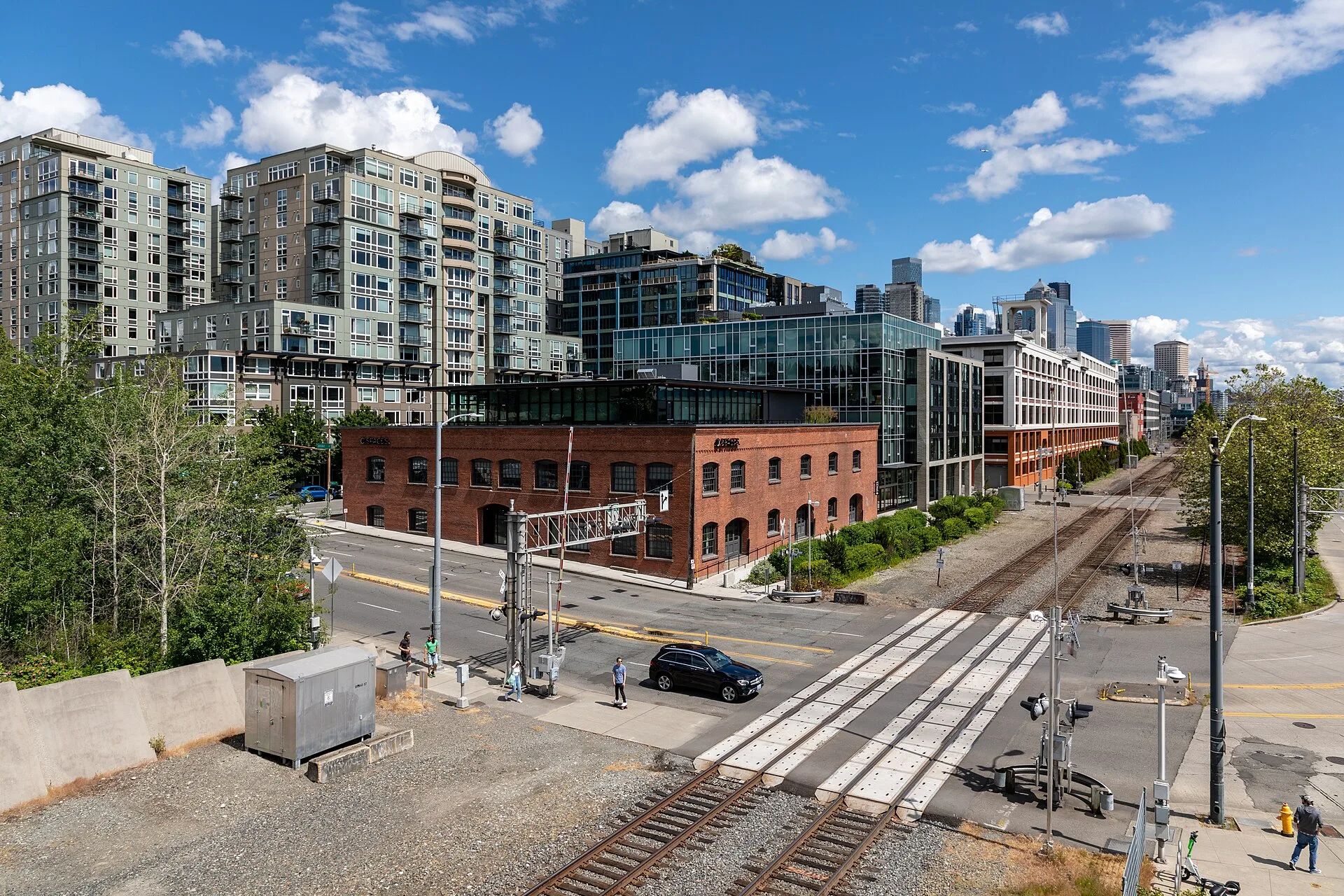 Brick and glass buildings beside railway tracks with apartment towers behind