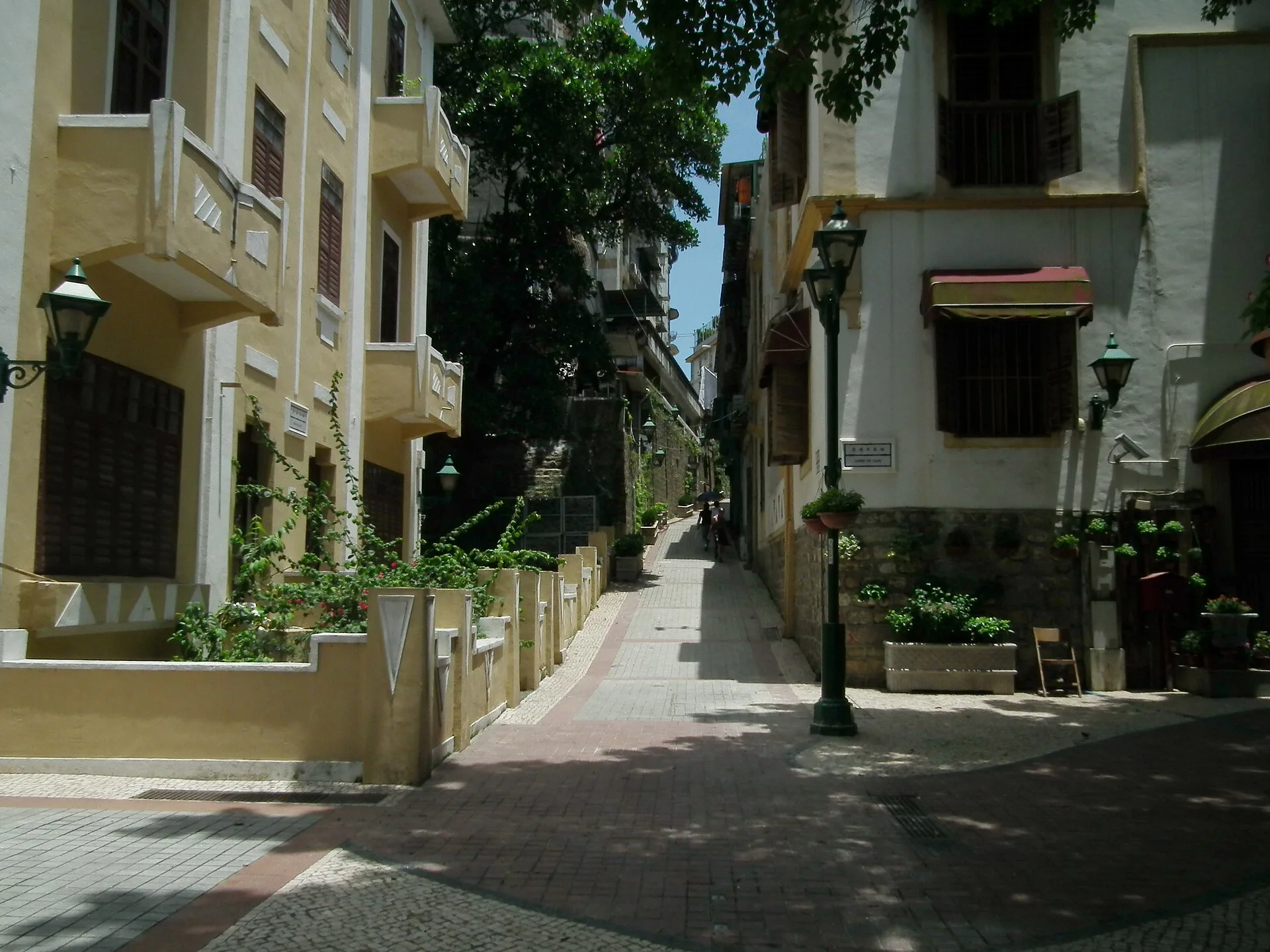 Quiet paved lane with pastel colonial houses, street lamps and trees