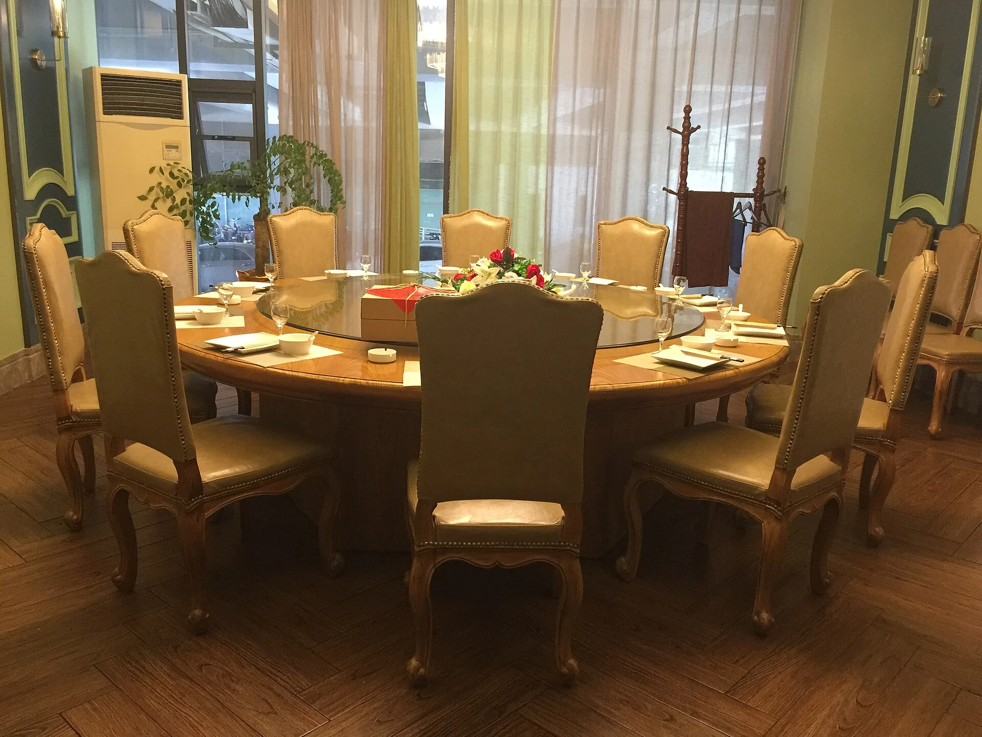 Large round dining table with a glass turntable surrounded by upholstered chairs
