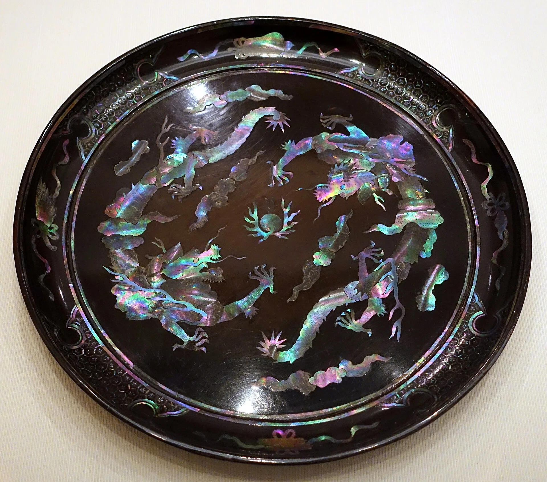 Round black lacquer tray inlaid with iridescent mother-of-pearl dragons and clouds