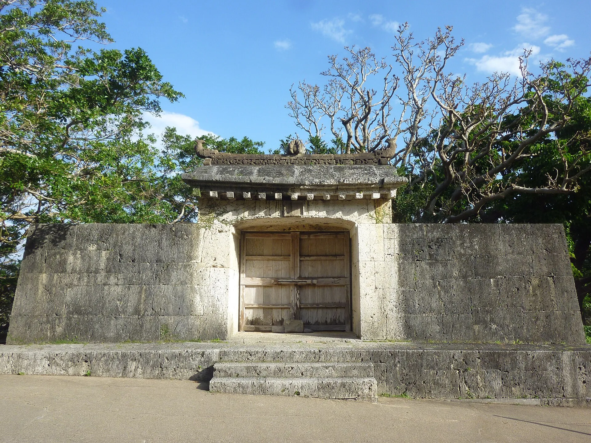 Stone gateway with a tiled roof set in a low limestone wall