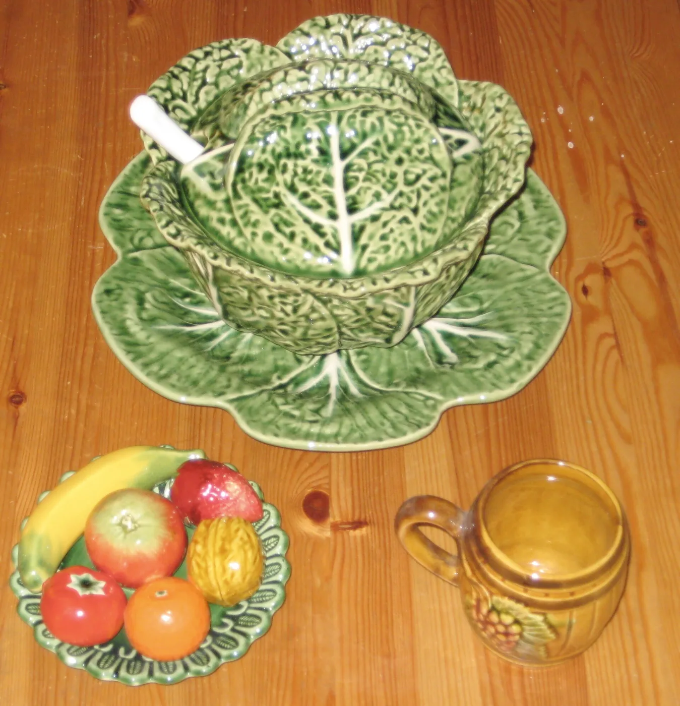Green cabbage-leaf tureen and plate beside a fruit dish and yellow jug