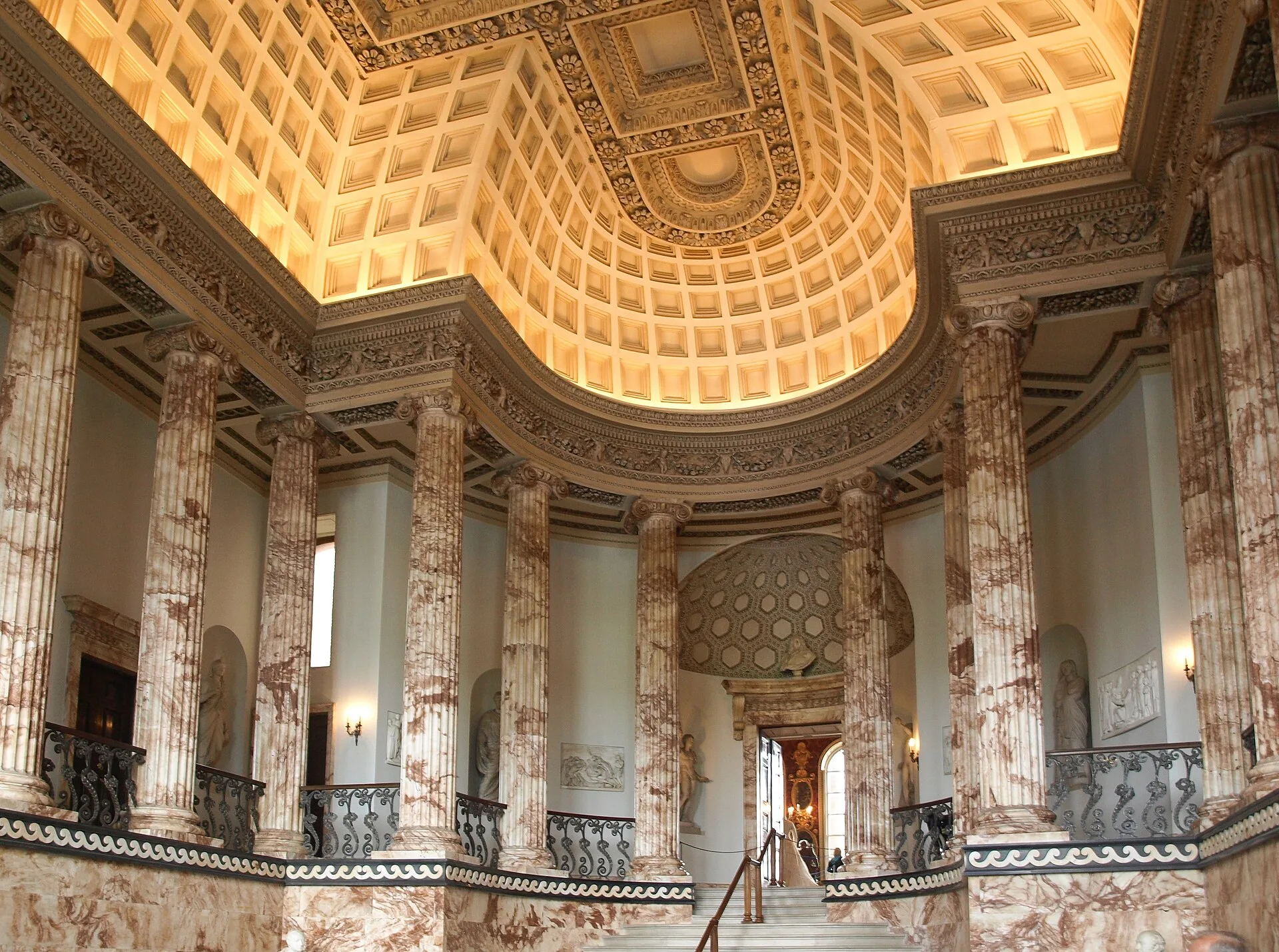 Hall with fluted marble columns, a coffered dome and a gallery staircase