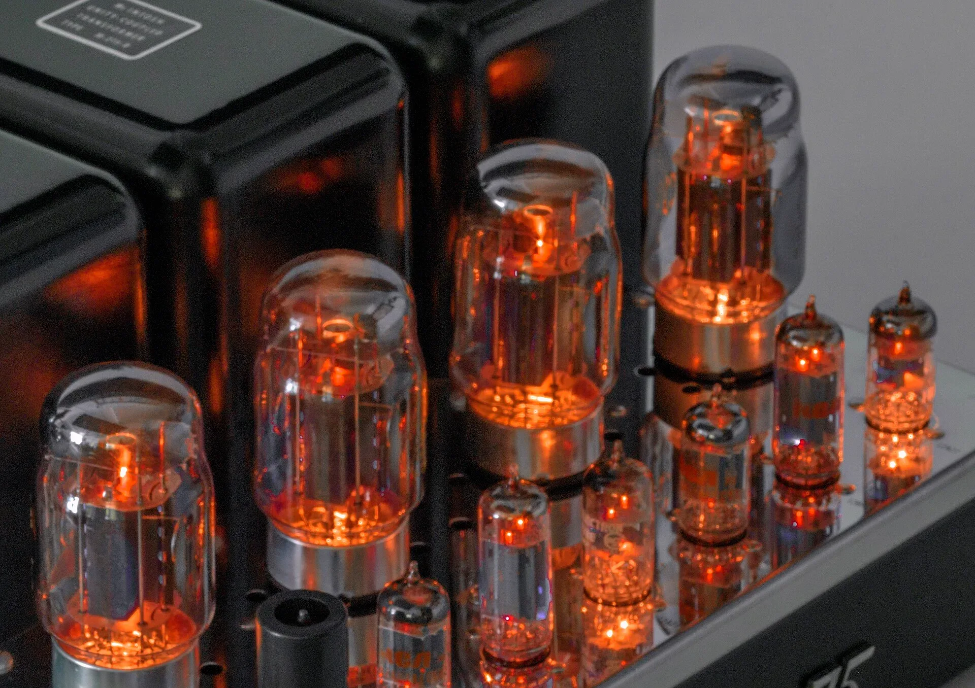 Glowing orange vacuum tubes standing on a polished amplifier chassis