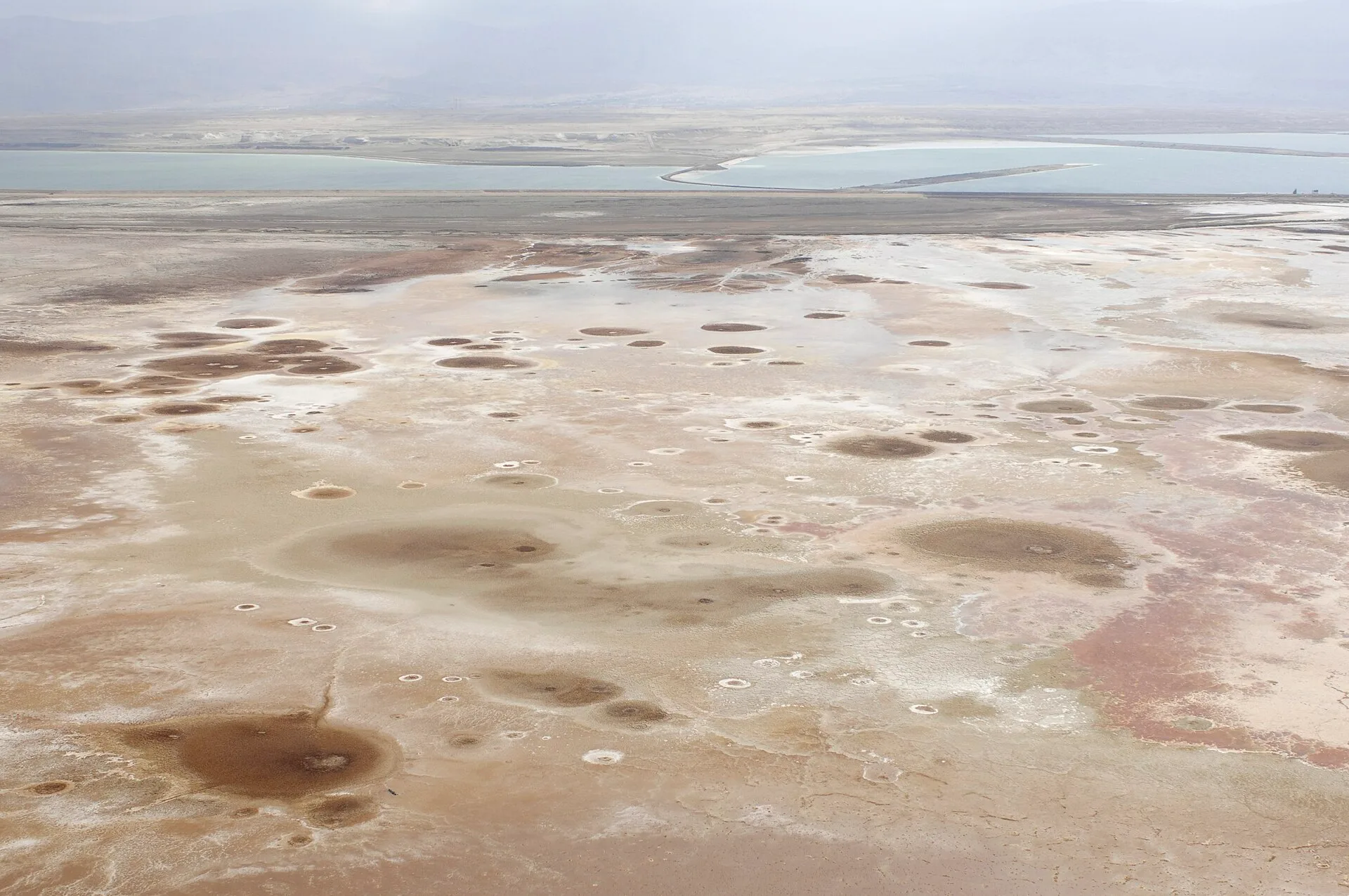 Aerial view of pale salt formations and pools stretching to the horizon