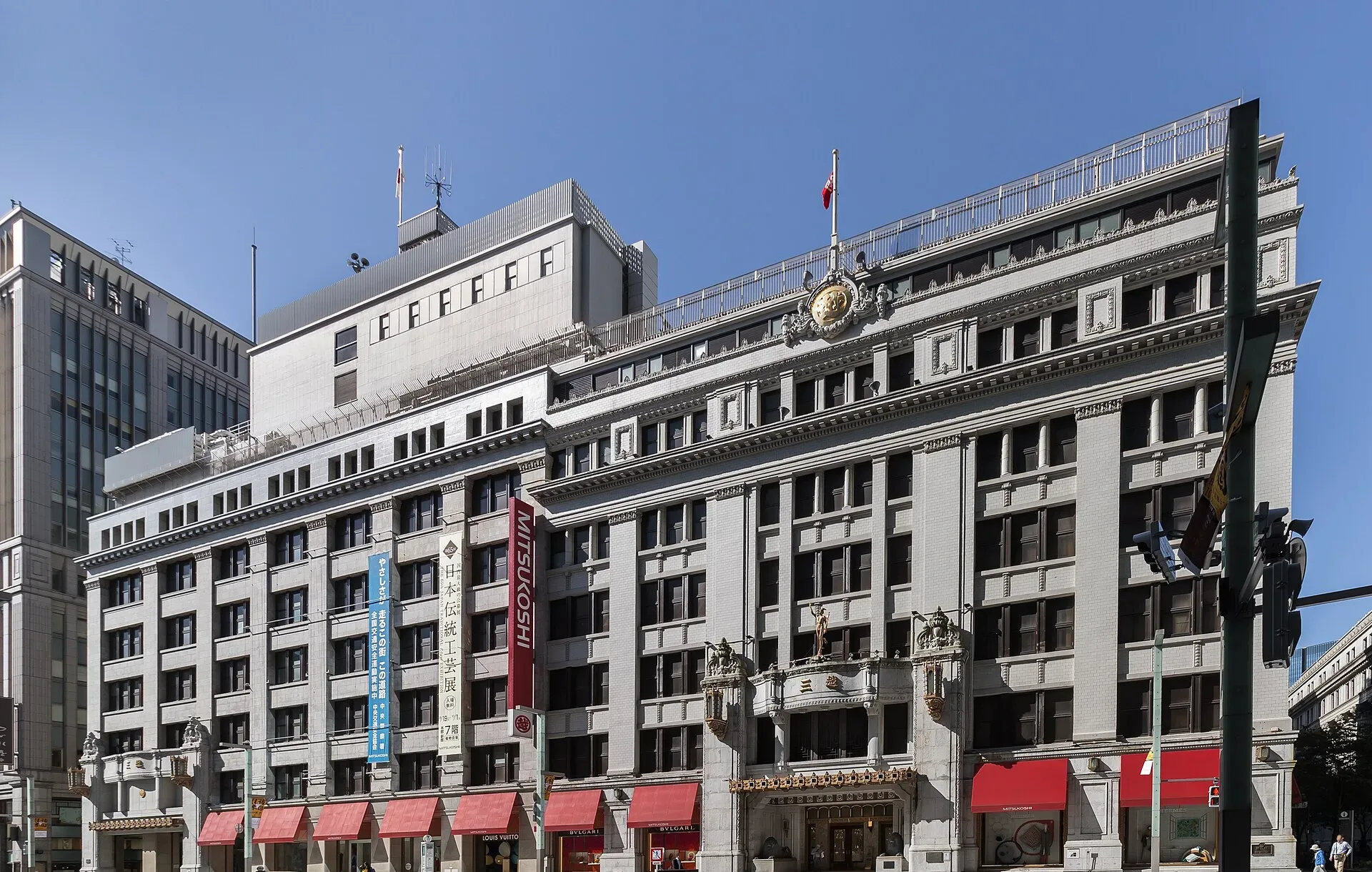 Stone department store building with red awnings on a sunny street corner