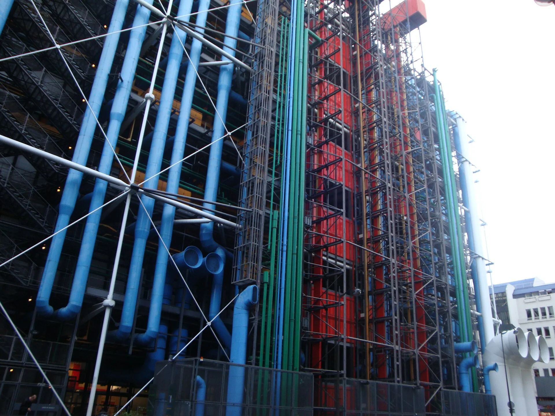 Blue, green and red pipes and steel bracing on a building facade