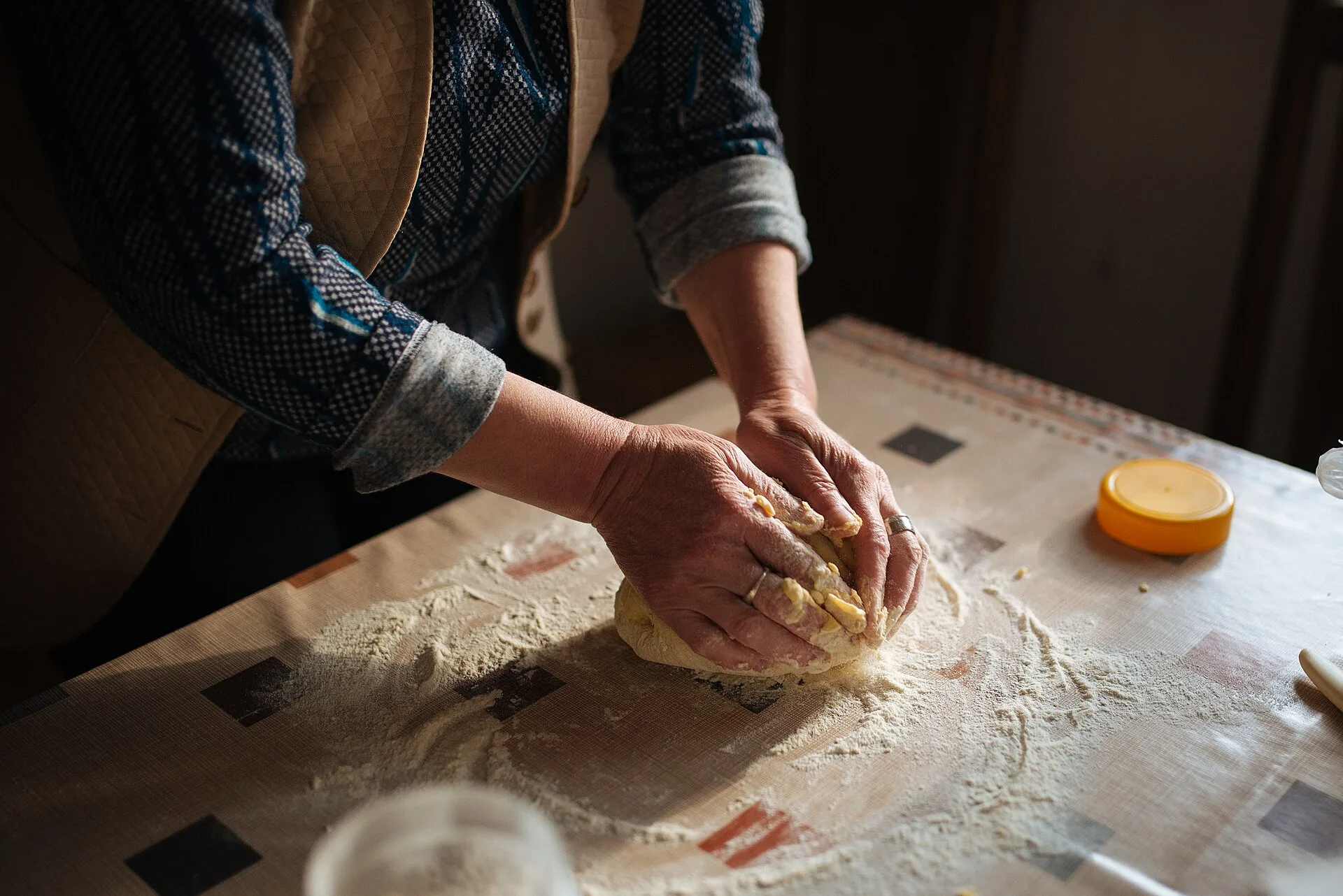 Hands kneading a ball of bread dough on a floured table