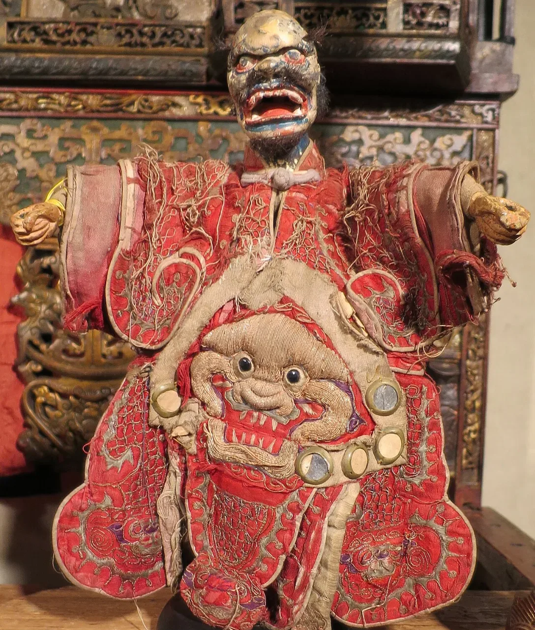 Hand puppet with a fierce carved face and embroidered red robe