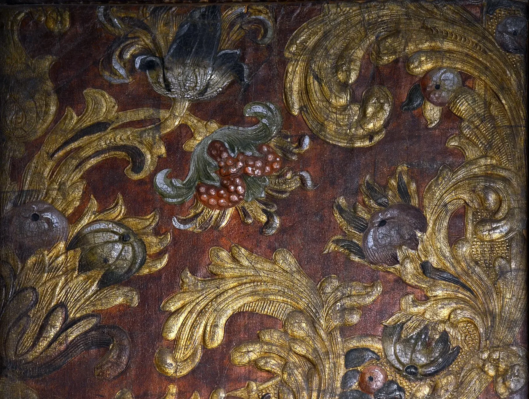 Gilded and painted leather with gold acanthus scrolls on a dark red ground