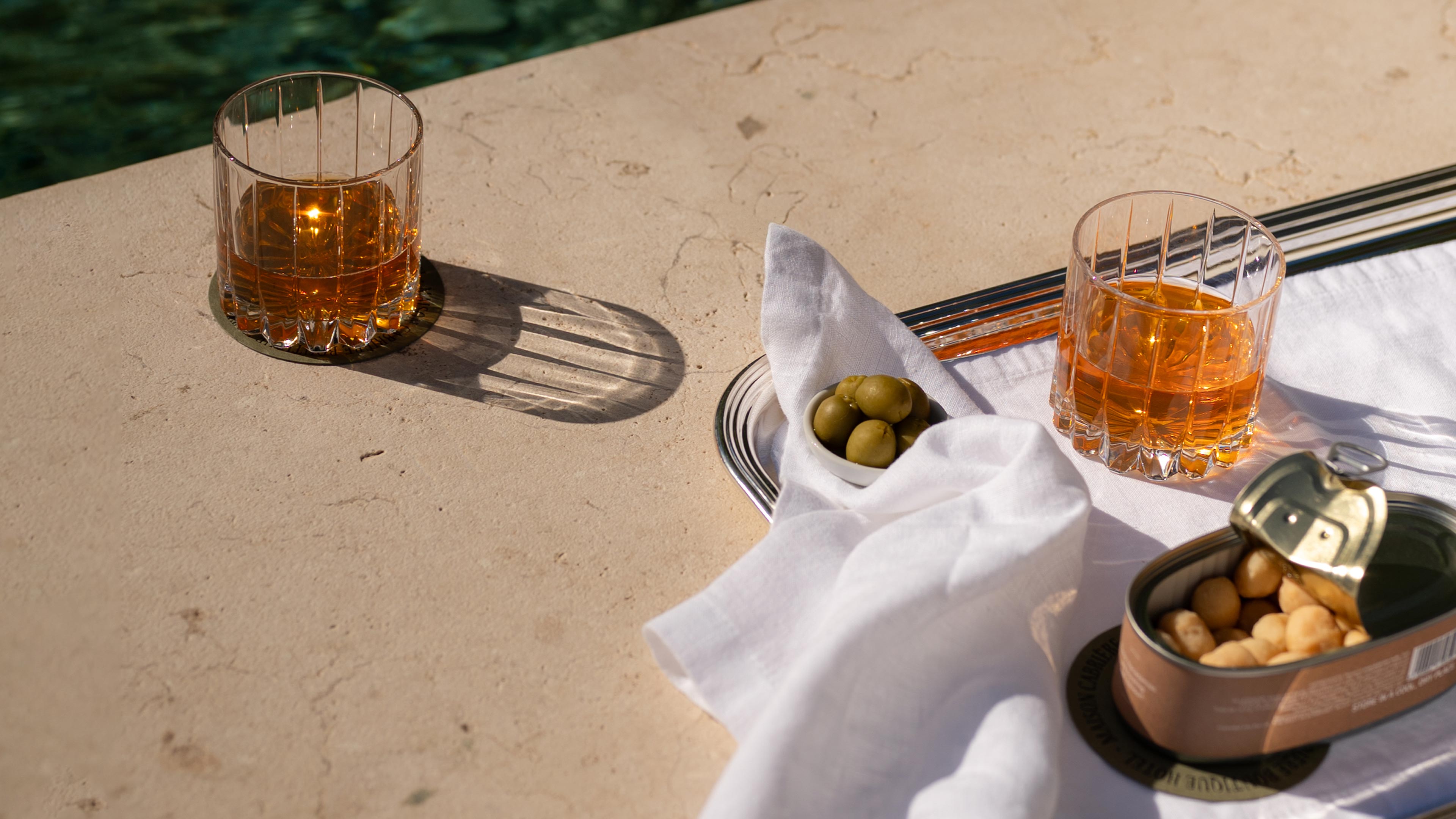 Pool scene with drinks and snacks served on a silver platter and luxury linen