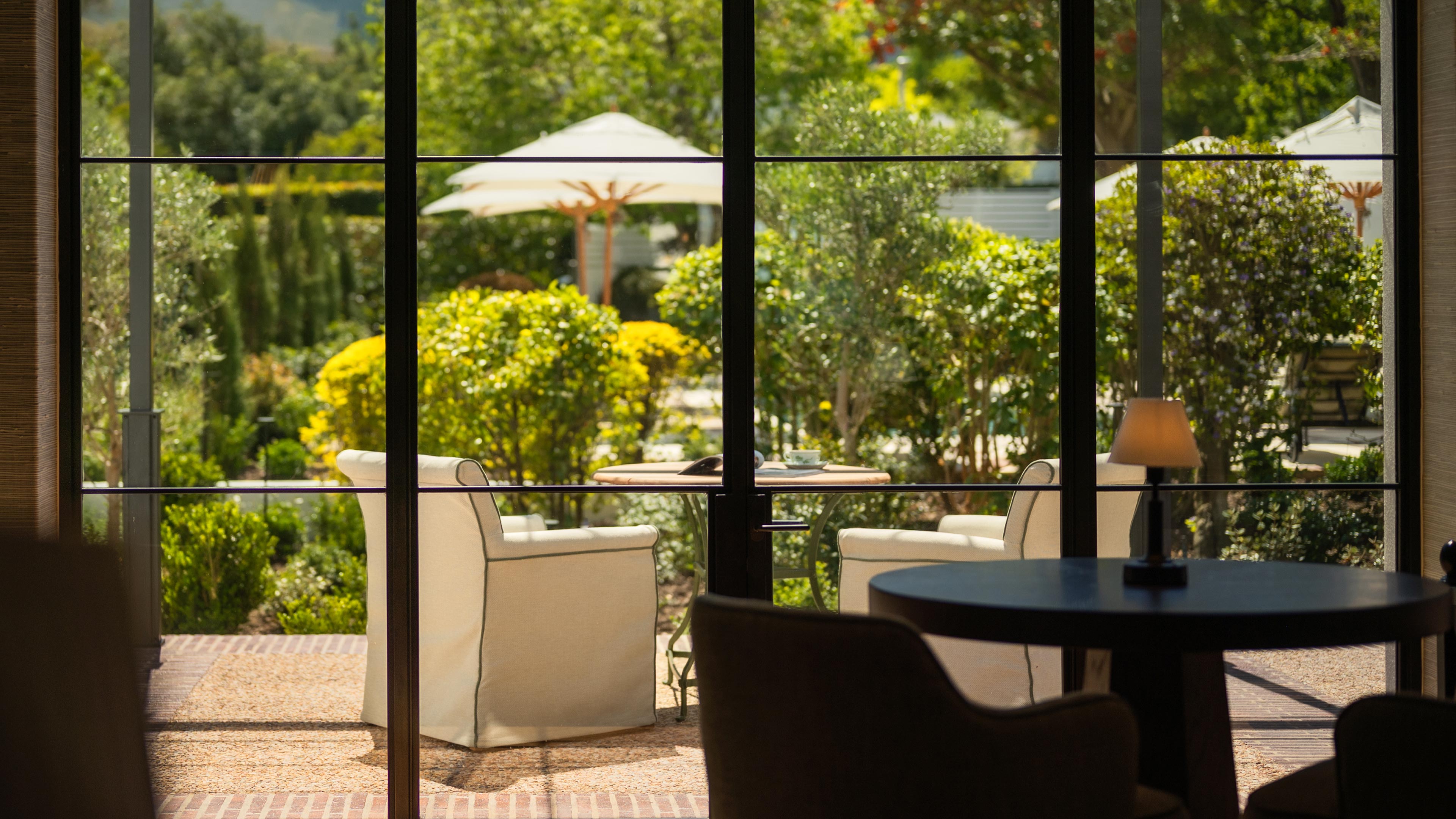 Luxury dining room interior with a view of a beautiful, lush green garden with patio furniture