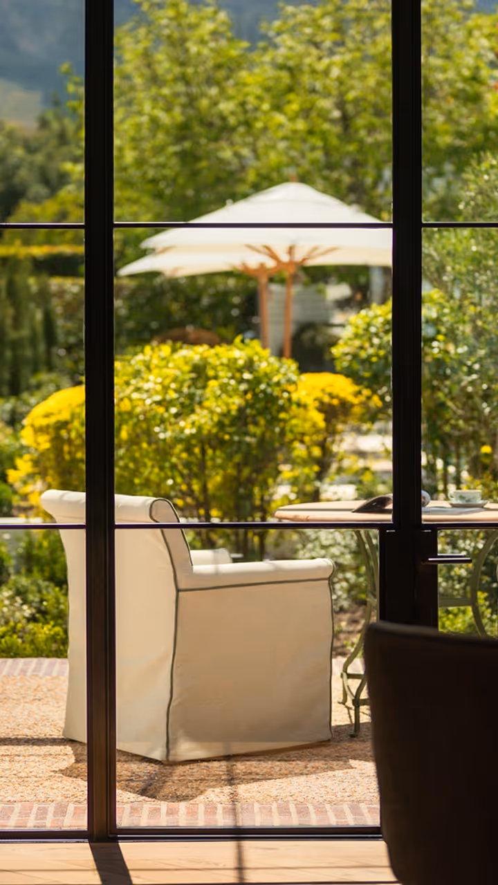Luxury dining room interior with a view of a beautiful, lush green garden with patio furniture