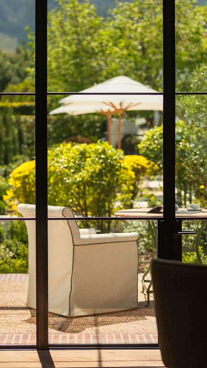 Luxury dining room interior with a view of a beautiful, lush green garden with patio furniture