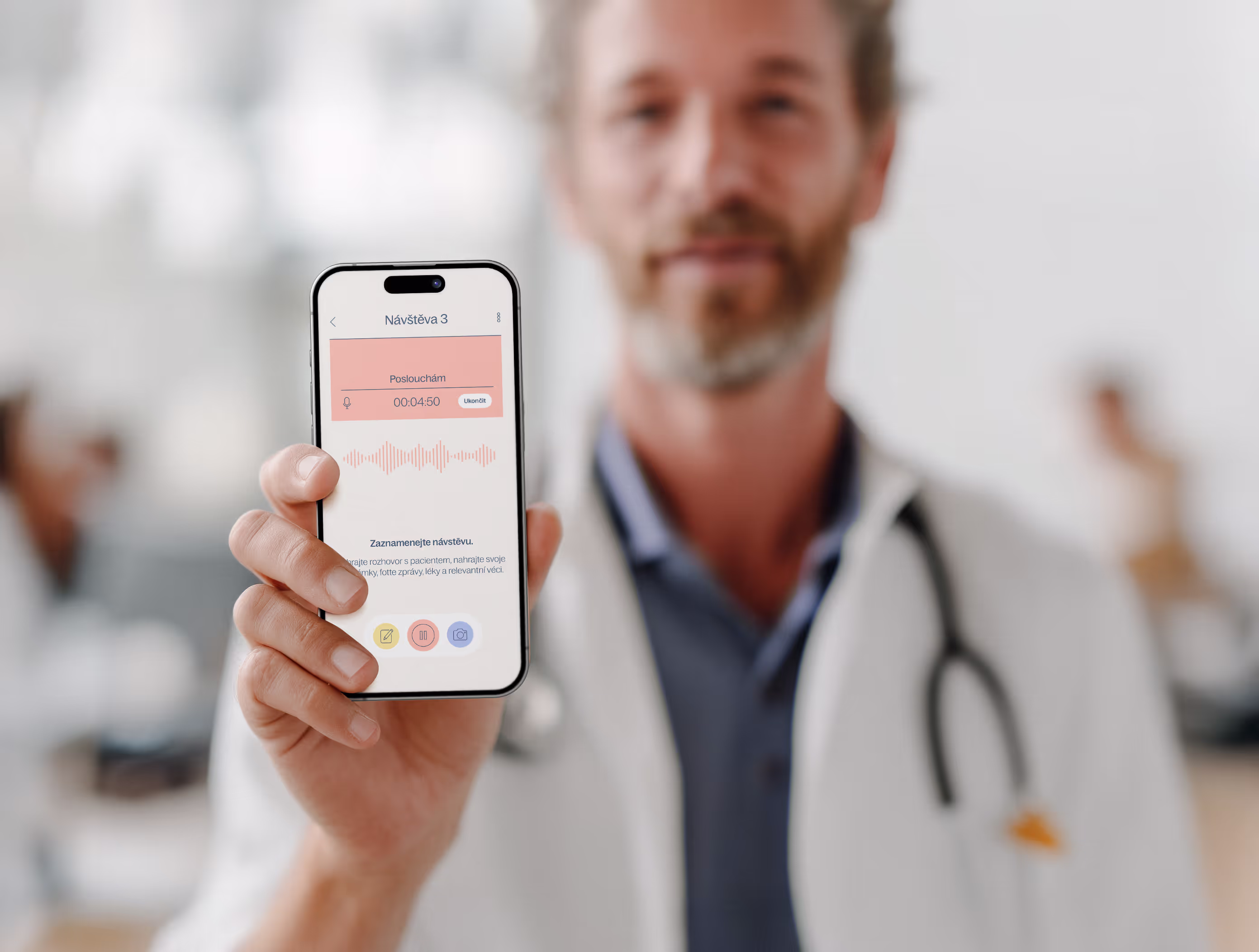 Doktor držící chytrý telefon s obrazovkou aplikace na nahrávání hlasu během návštěvy pacienta.