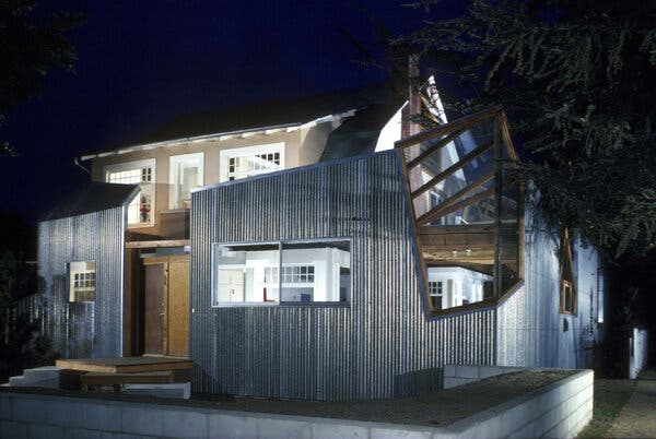 A boxy, fractured looking house seen at night, lighted from below.