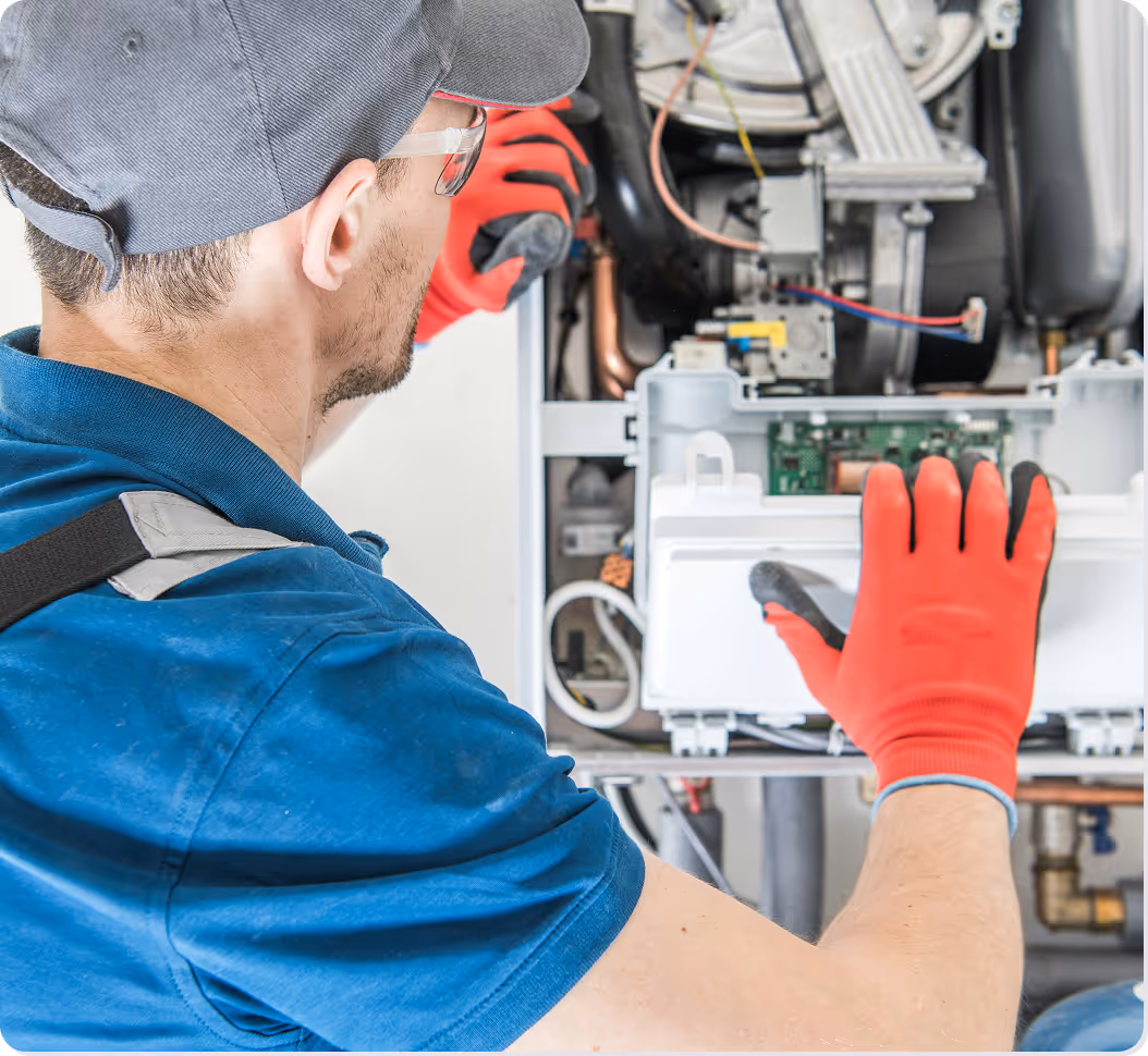A man wearing a blue shirt and red gloves working on a machine.