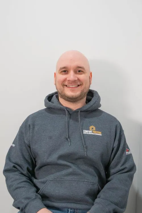 A bald man wearing a grey hoodie with a logo on it.