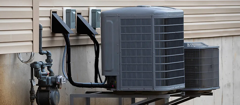 A large grey air conditioner is sitting on a metal stand.