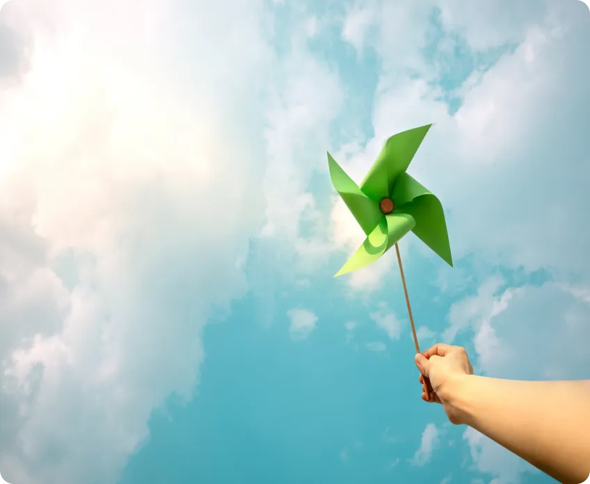 A person is holding a green kite in the sky.
