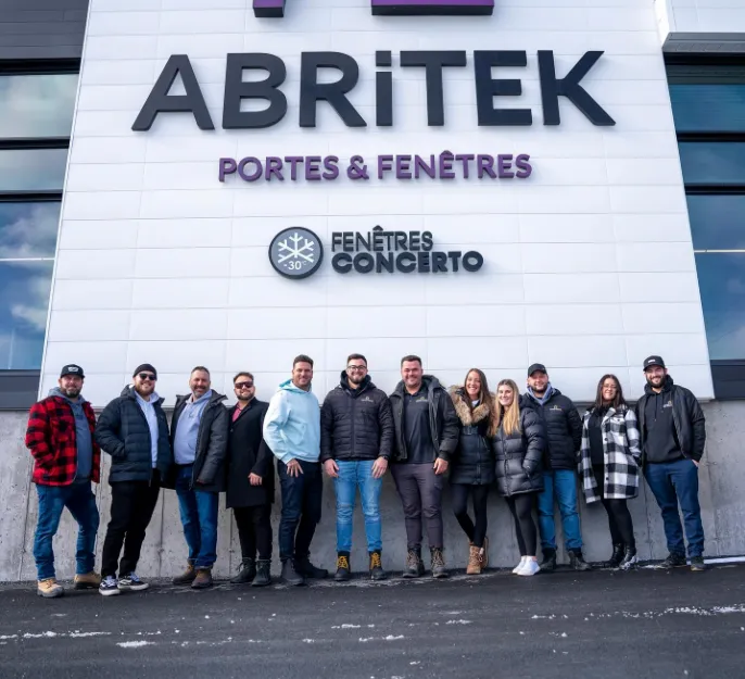 A group of people standing in front of a building with the name Abritek on it.