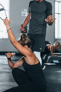 Woman working out at gym getting an instructed workout to show our full body workouts encompassed in our total wellness
