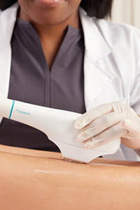 Woman placing a laser hair removal head on a lubricated leg