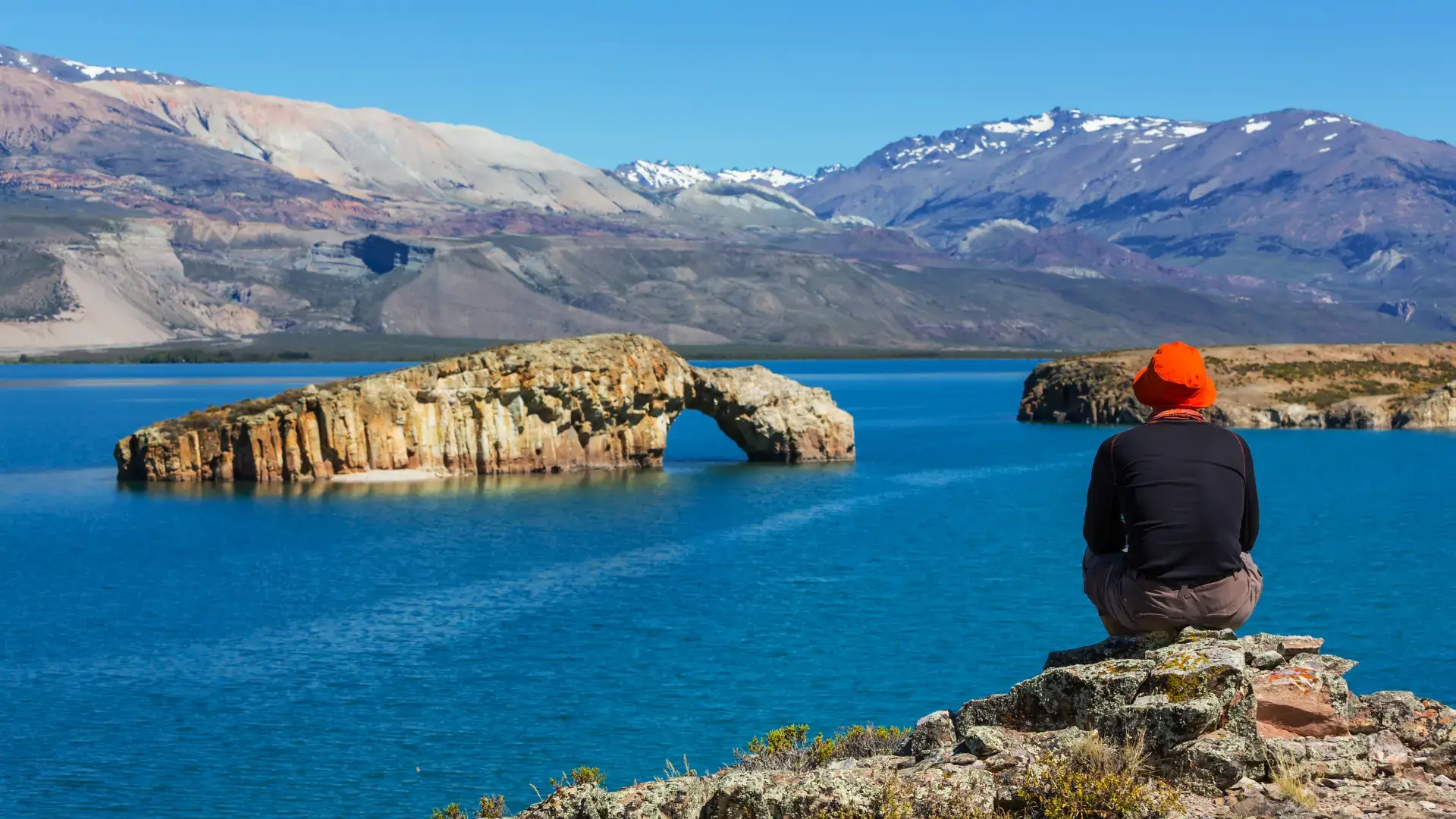 A man looks off across the ocean to a range of mountains