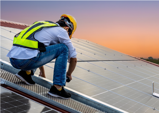 An electrician installing solar panels on the roof of a commercial building.