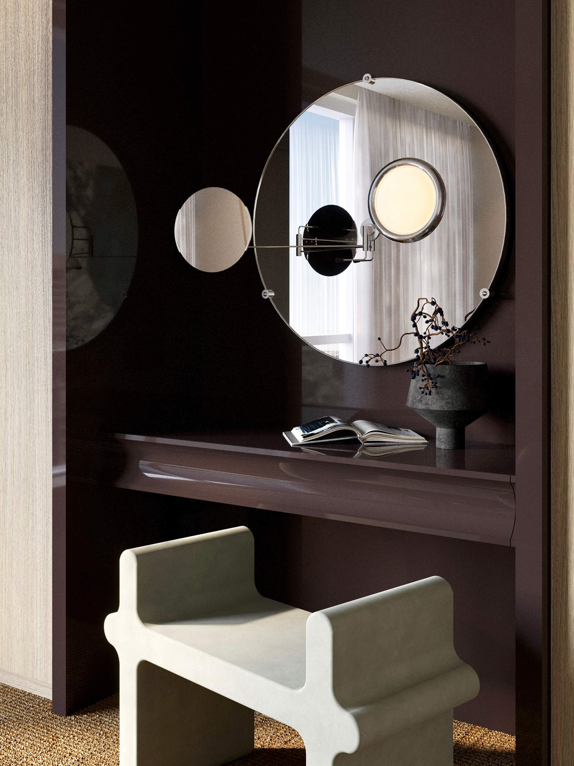 Close-up of a bespoke vanity area with a high-gloss backdrop and Eileen Grey Satellite mirror. A sculptural stool by Giobagnara stands in front of a sleek dark desk. Minimalist décor and soft lighting create a refined atmosphere. {vertical}
