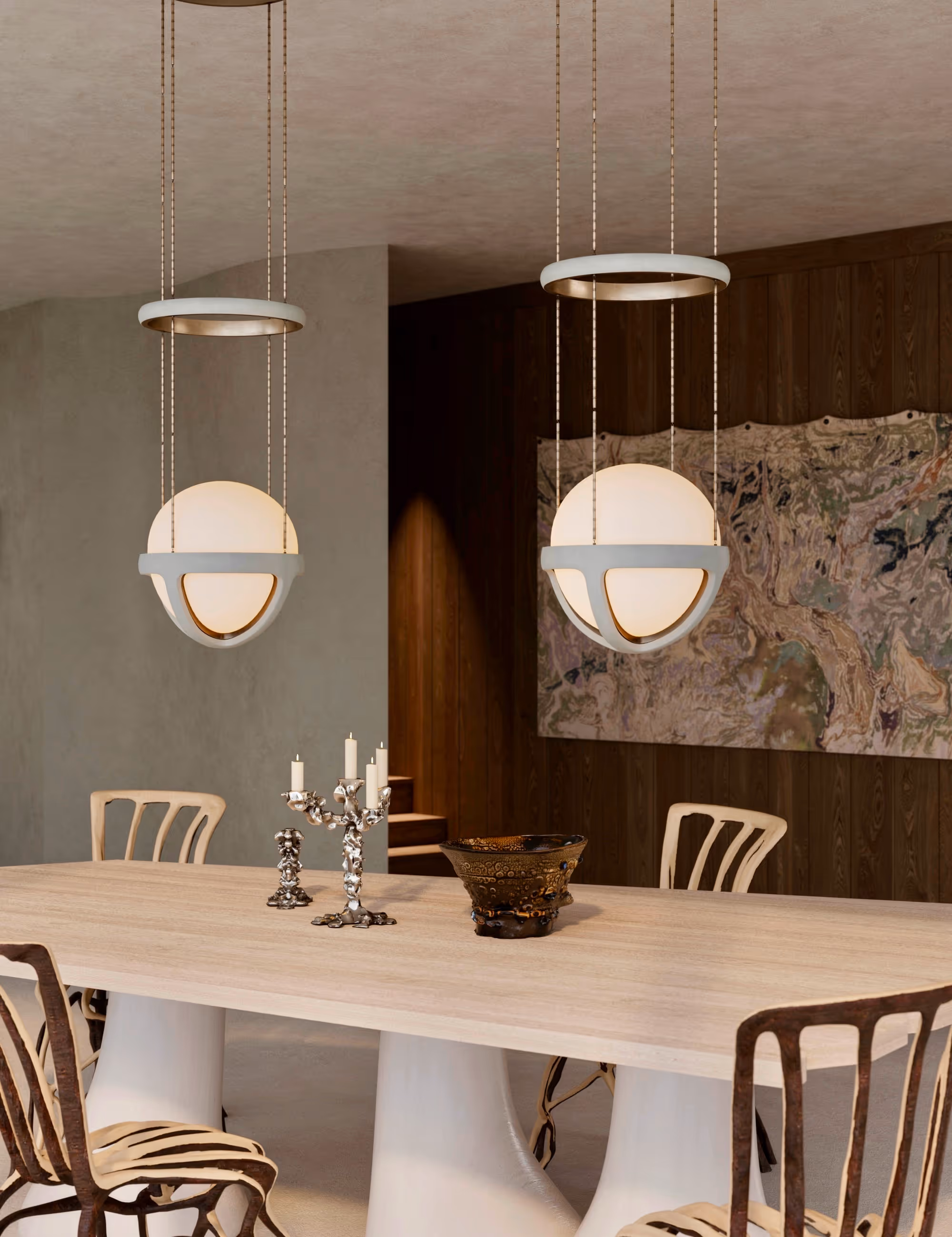 Close-up of the dining area with sculptural fiberglass-based table, Fullgrown tree chairs, and Apparatus pendant lights, set against a dark wooden wall and abstract artwork. {vertical}