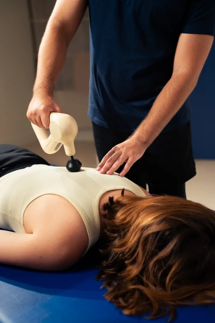 Une femme effectue une posture de yoga dans un espace lumineux, les bras tendus en arrière et une jambe fléchie en avant. Elle porte un ensemble de yoga beige et semble concentrée tout en pratiquant une posture d’étirement.