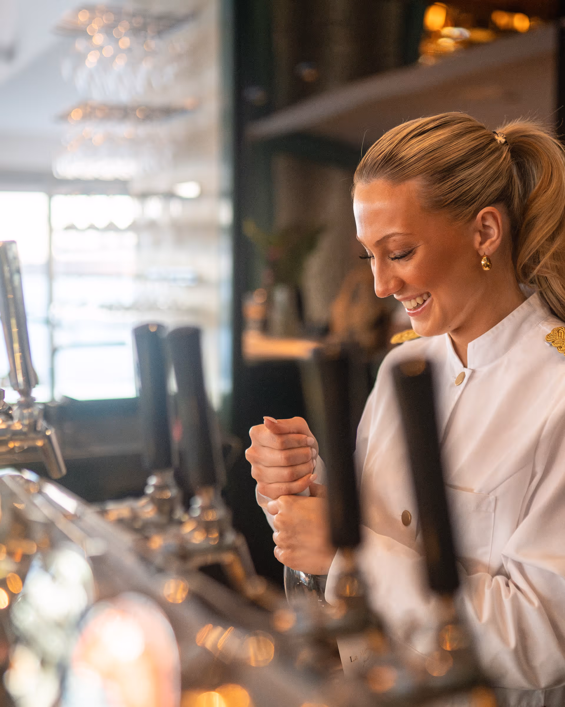 Teammedlem från hovet på Verandan står och häller upp ett glas för en gäst