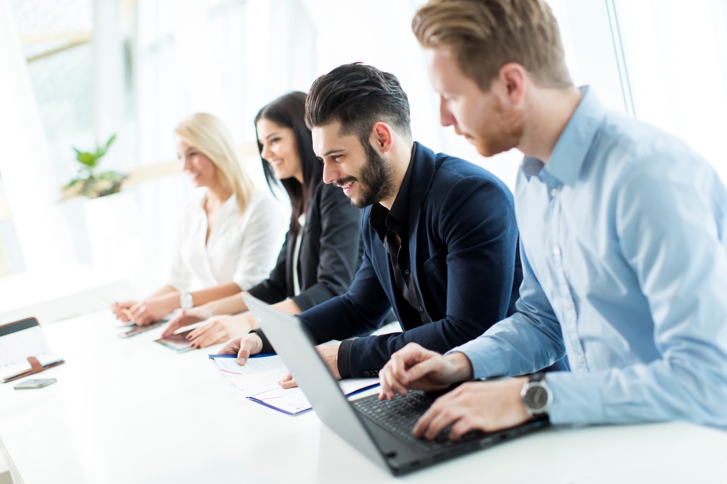 Grupa pracowników siedzących w biurze uczestniczących w spotkaniu. 