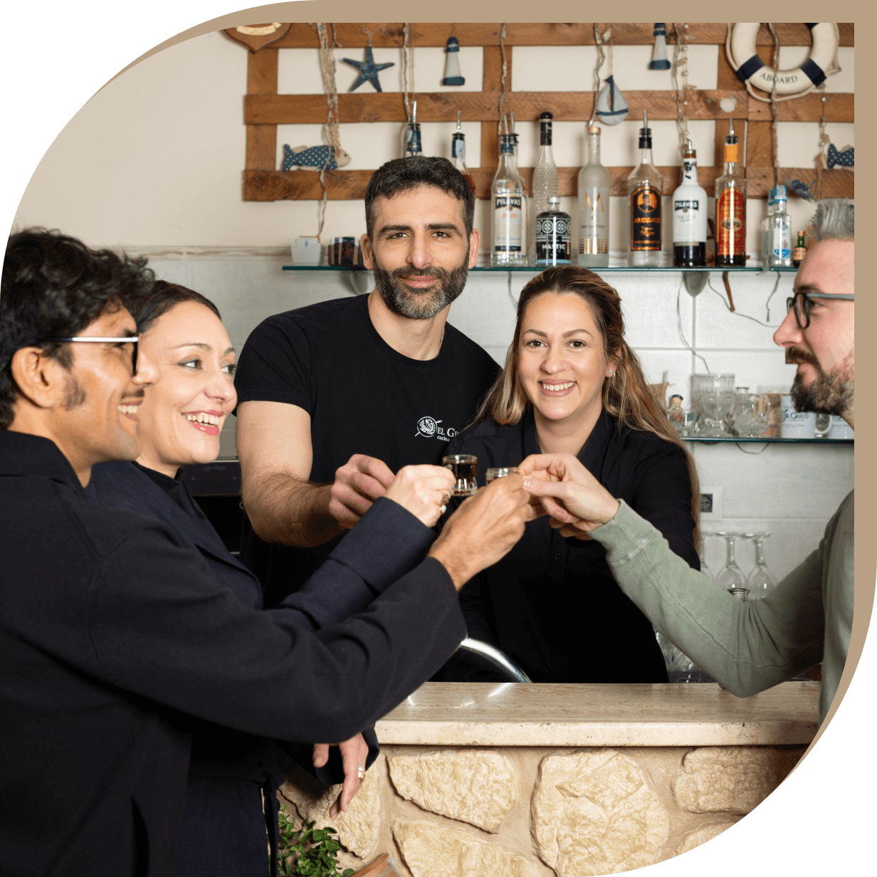 Staff e clienti del Ristorante El Greco di Bologna brindano insieme al bancone.