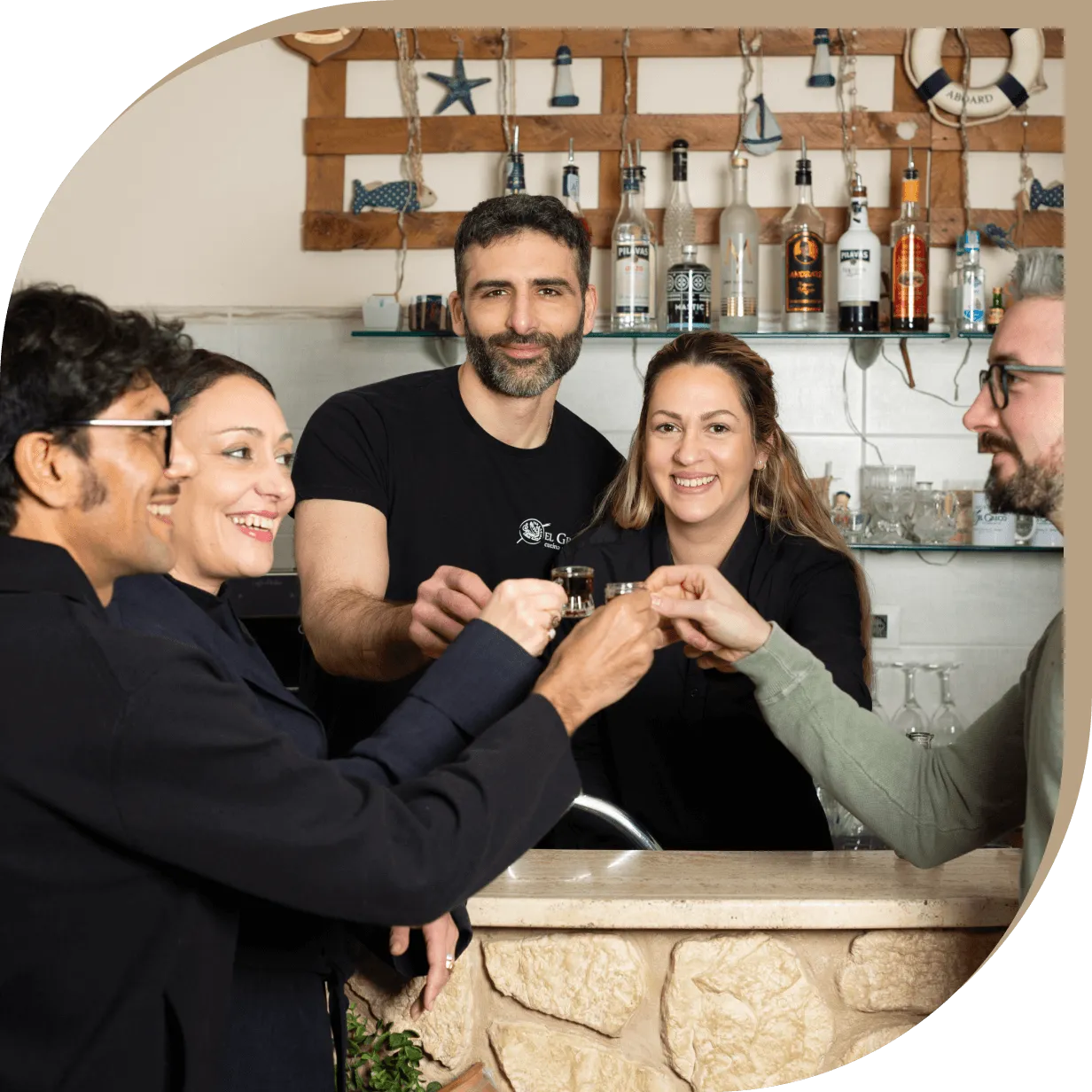 Staff e clienti del Ristorante El Greco di Bologna brindano insieme al bancone.