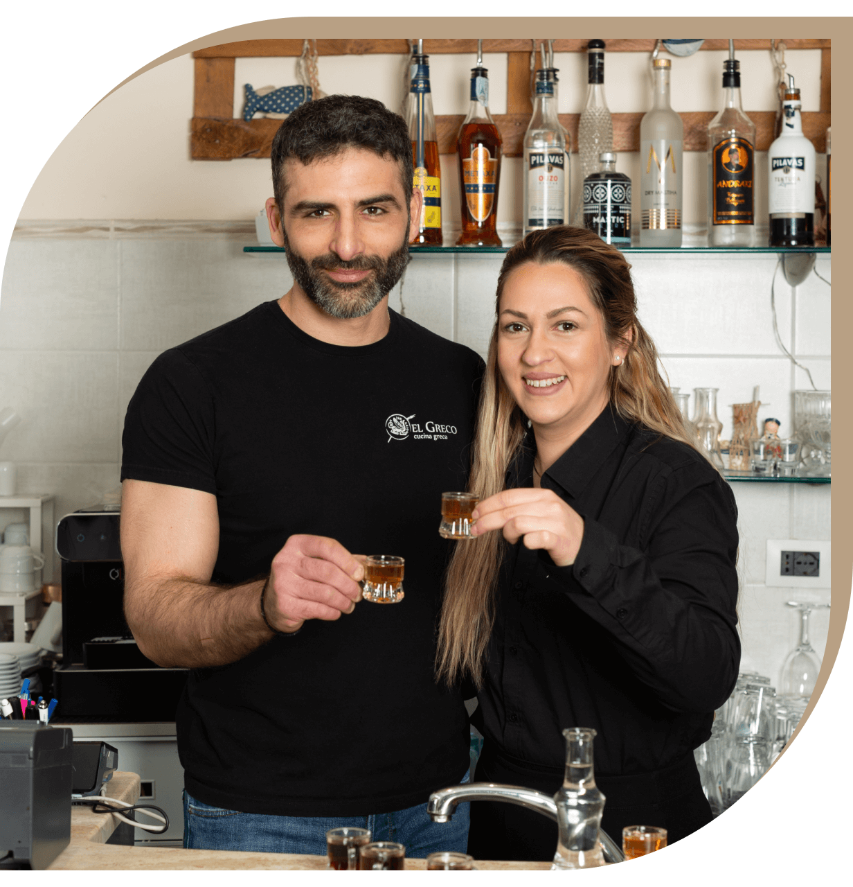 I proprietari del Ristorante El Greco di Bologna brindano insieme al bancone.