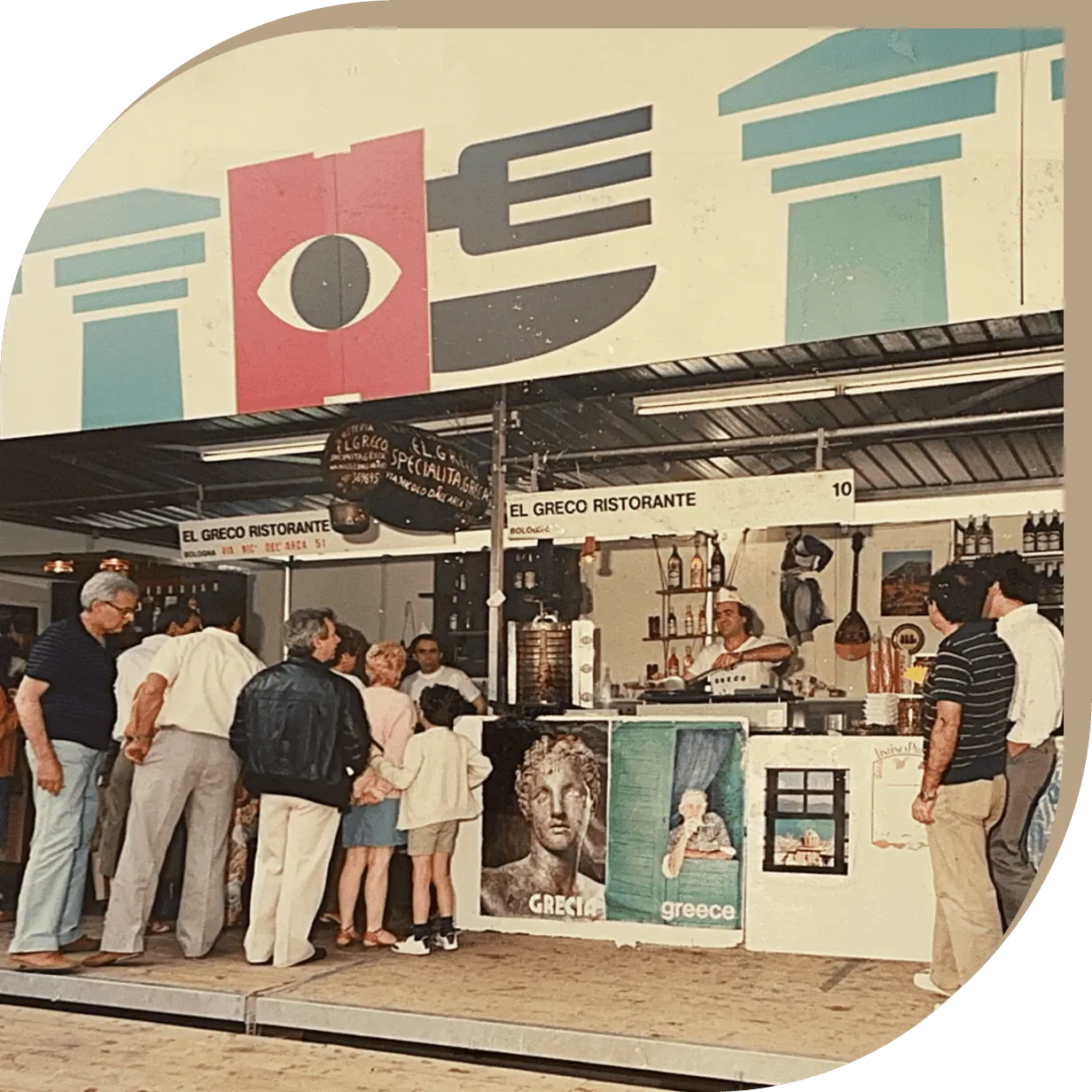 Stand del Ristorante El Greco alla Fiera di Bologna con il fondatore che serve piatti greci.