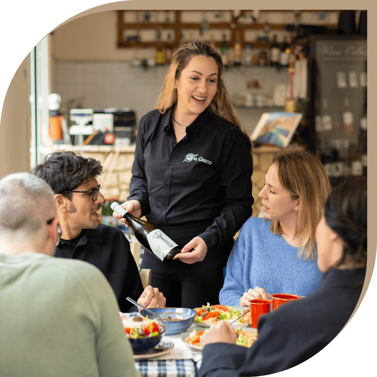 La proprietaria del Ristorante El Greco di Bologna serve vino ai clienti durante il pranzo.