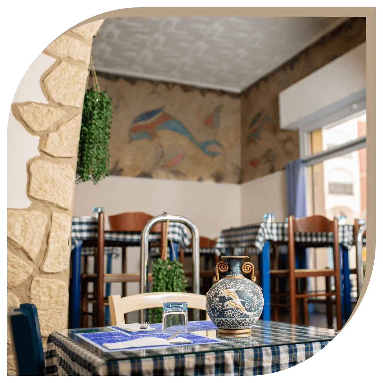 Ingresso del Ristorante El Greco di Bologna con tavoli in legno e tovaglie a quadri blu e bianchi.