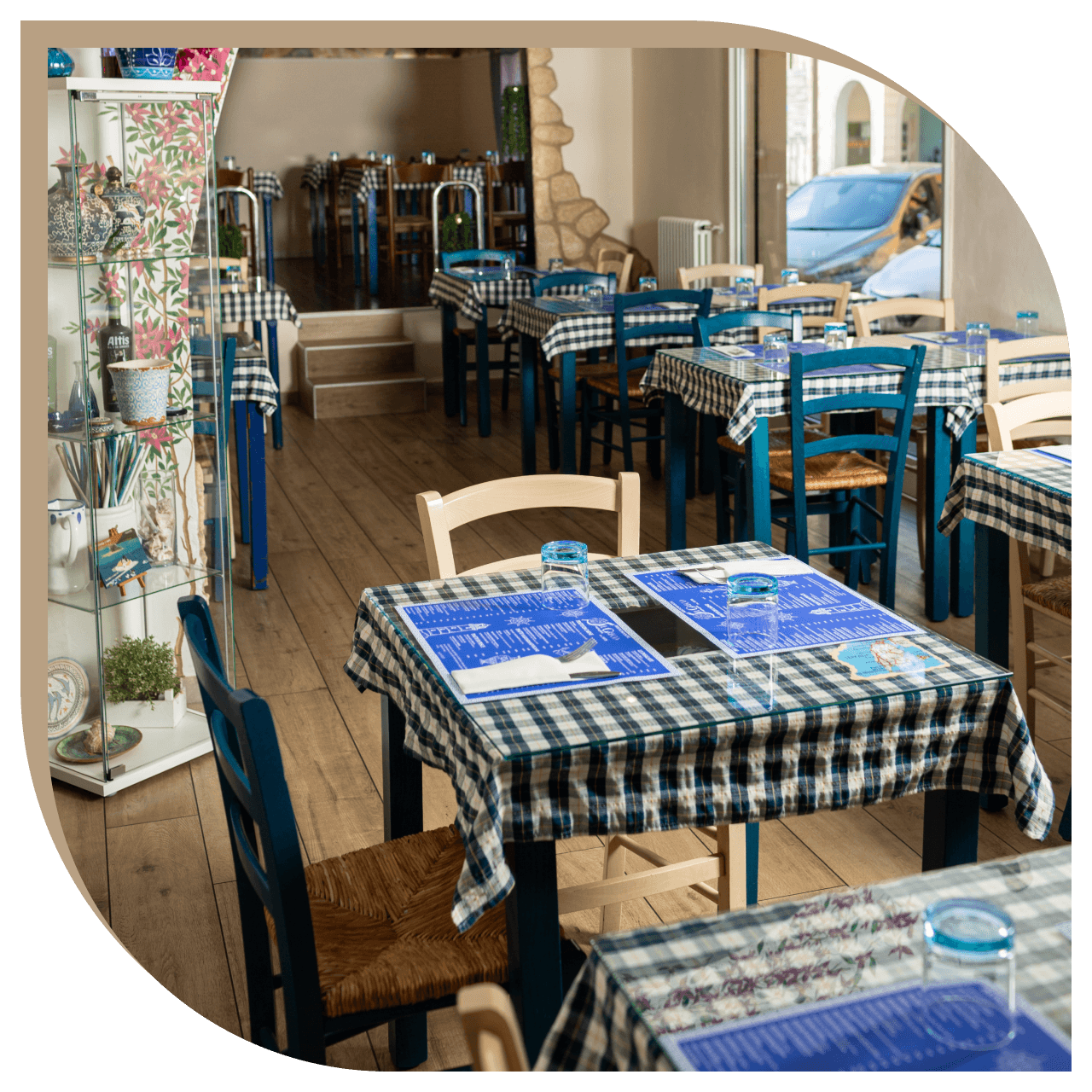 Dettaglio dei tavoli del Ristorante El Greco di Bologna con vaso greco e affresco dei delfini sullo sfondo.